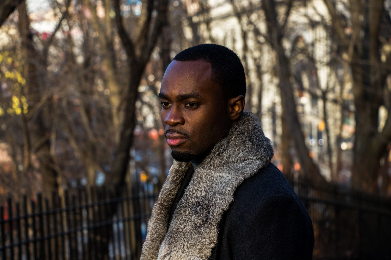 Portrait of a man wearing a fur-collared coat outdoors in winter.